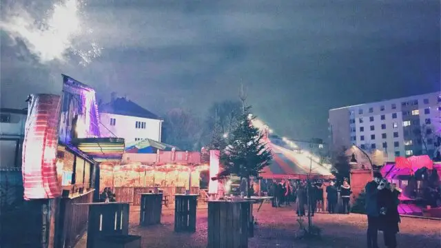 Märchenbazar Christmas Market in Munich with colorful tents, fairy lights, and festive atmosphere near Olympiapark, Germany.