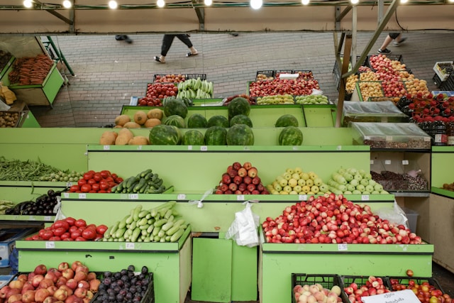 Fresh fruits and vegetables on display at a local farmers market with green produce stands